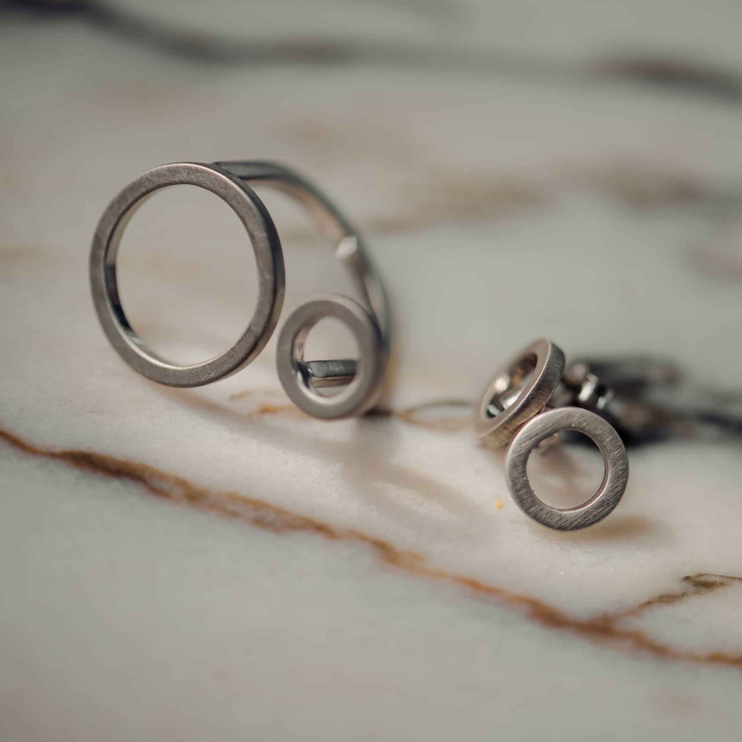Der Ring und die Ohrstecker CIRCULAR bestehen aus 925er Sterlingsilber und einer dünnen Schicht Rhodium
