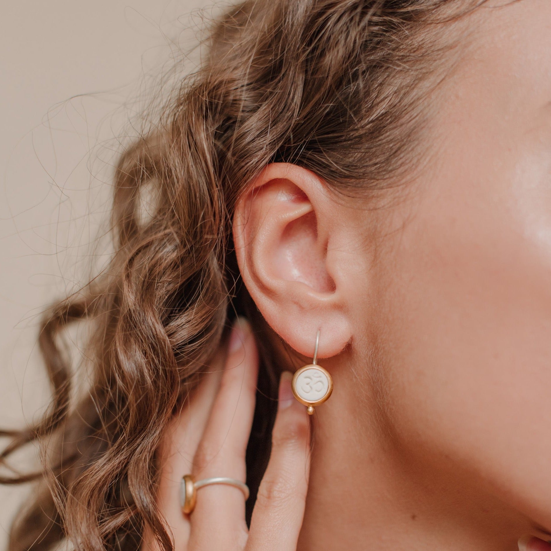 Die Ohrhänger OHM bestehen aus Sterlingsilber, einer galvanischen Vergoldung sowie Porzellan