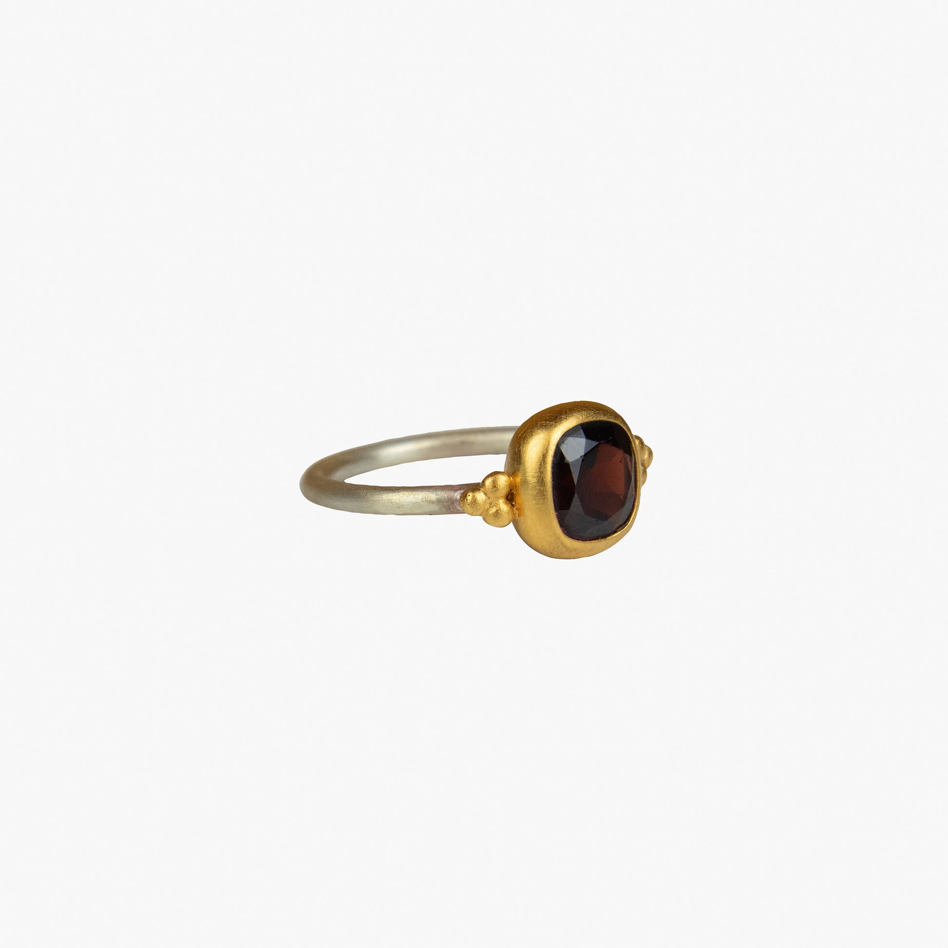 Der Ring KAYA besteht aus Sterlingsilber, einer galvanischen Vergoldung sowie einem Granat-Stein
